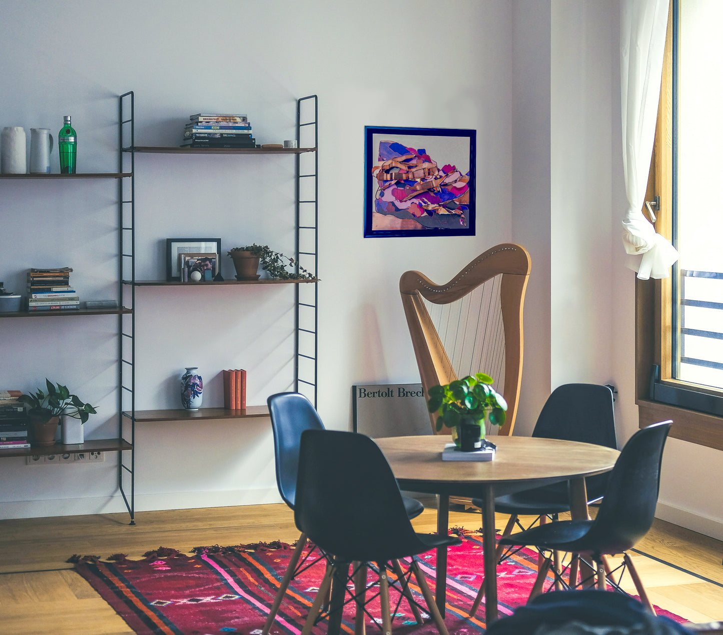 This in situ photo shows Switchbacks on a white wall next to a wire bookshelf. The room has a small dining table rug and light is coming in from a large window. 