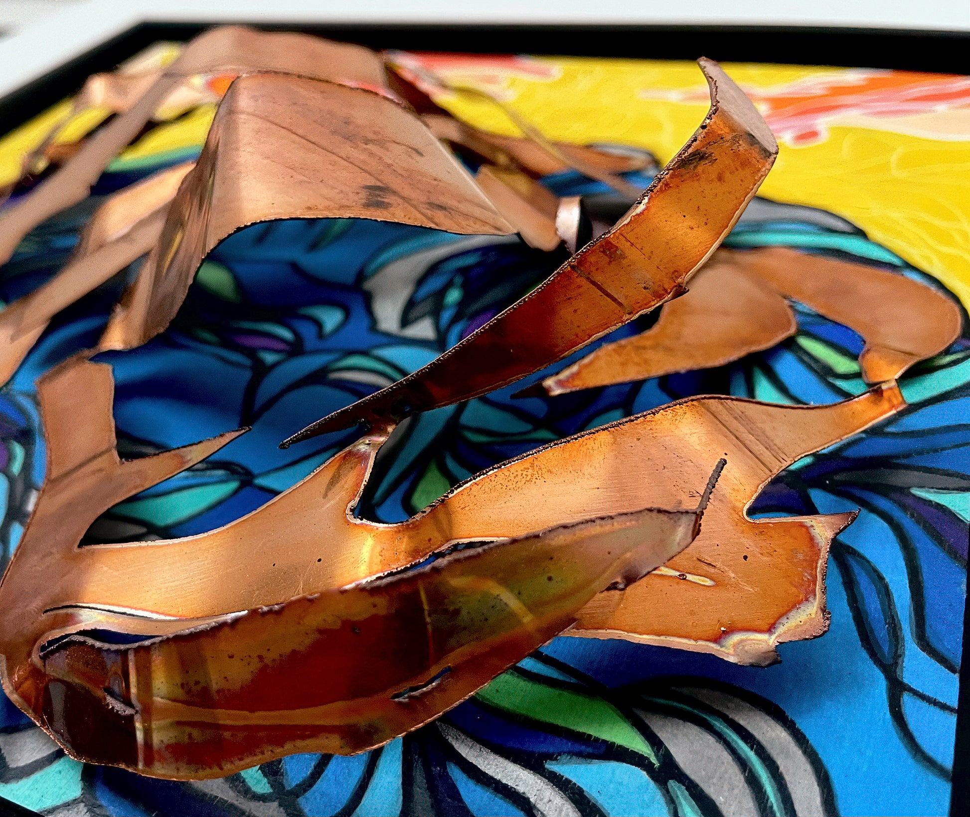 This image shows the three dimensional aspect of the artwork as the copper pieces lay atop the acrylic blues and yellows. 