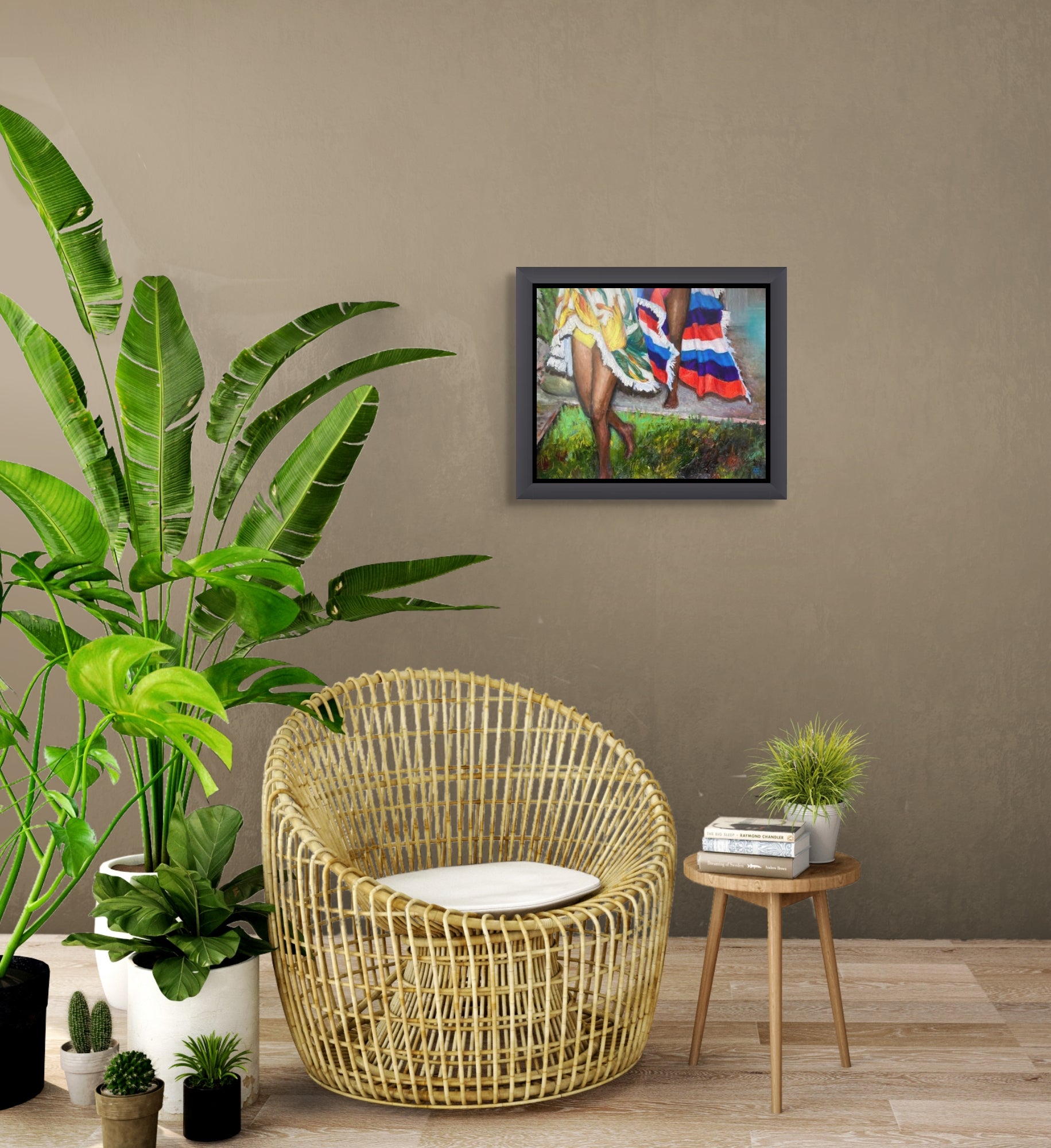 The framed painting is shown hanging on the wall above a wicker  chair, small table and large palm plant.