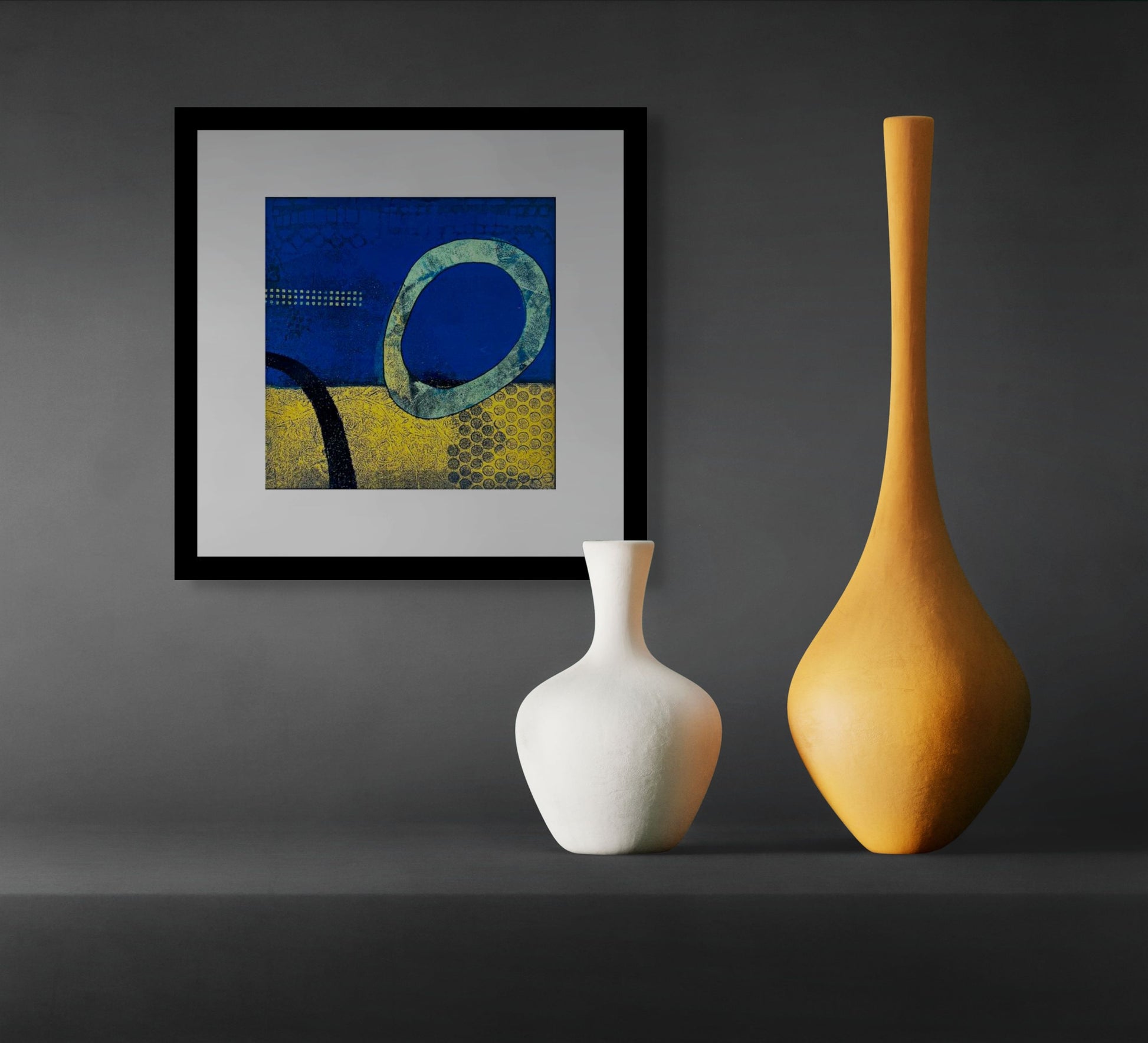 Abstract art piece with blue and yellow background and black textured elements; frame of white mat and black wood; artist Bob Hogue; shown in situ on grey wall with small white and tall yellow sculptural vases