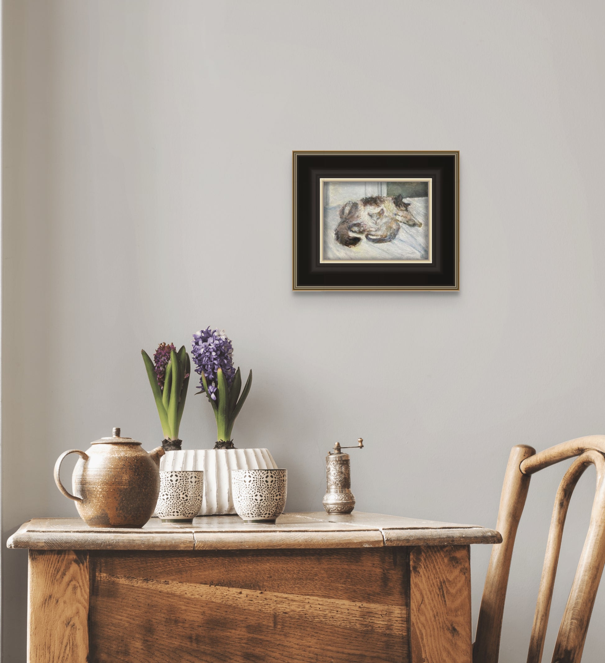 Close is shown hanging above a rustic table with coffee mugs and a plant. The painting is framed in a black frame with small white trim between the image.