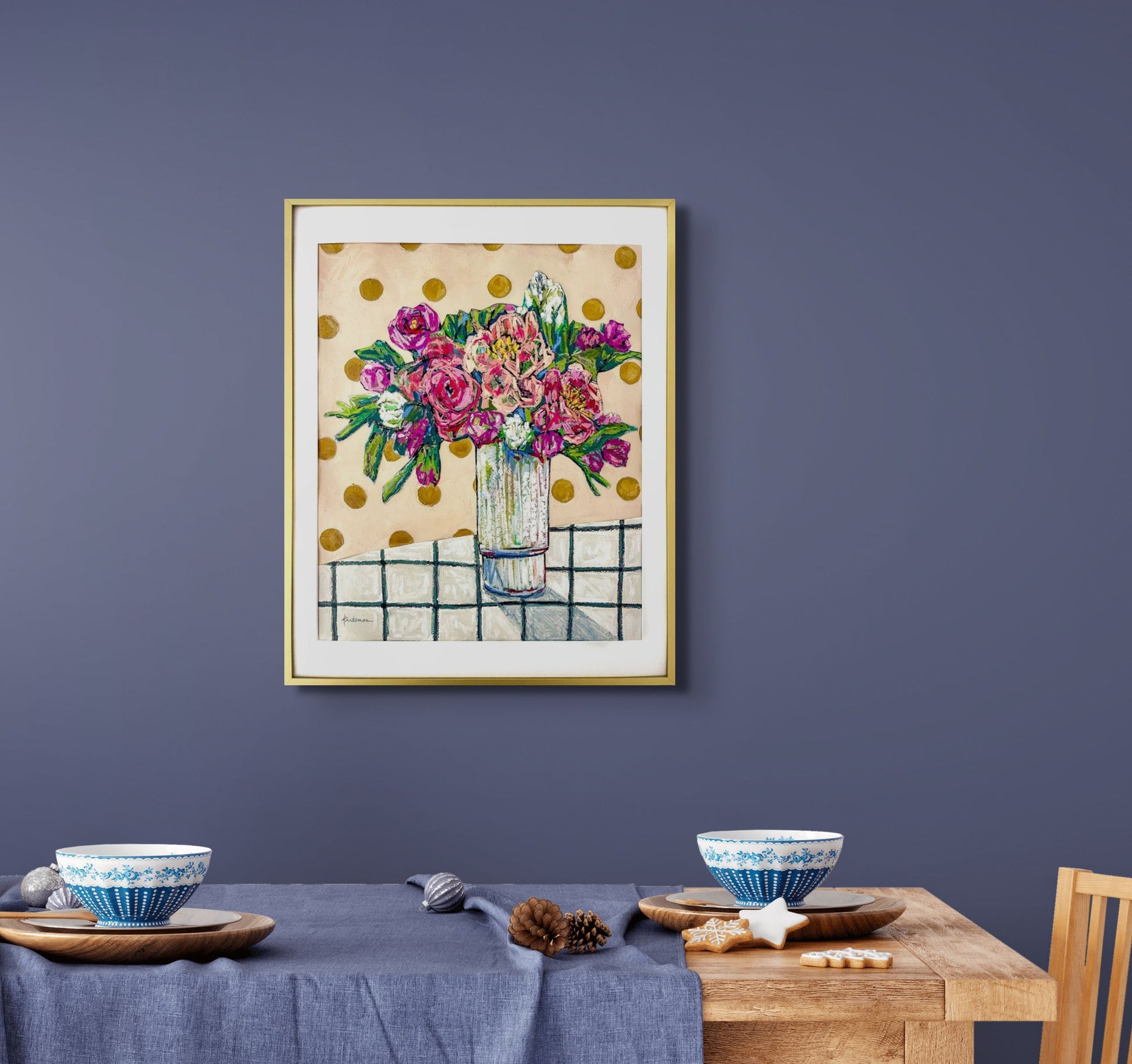 Painting and collage of mixed bouquet of flowers in a clear vase, sitting on a white/black checked tablecloth and against a beige background decorated with dark yellow circles;  shown framed and in situ on a lavender wall over a dining table; artist Rachel Bunteman