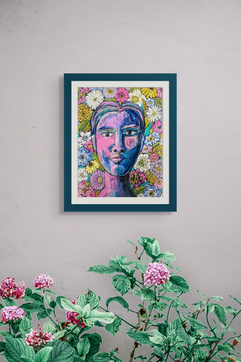 In situ image shows the abstract portrait Garden Repose hanging on a light gray wall over a flowering plant. The frame, not included, is teal with a white mat. 