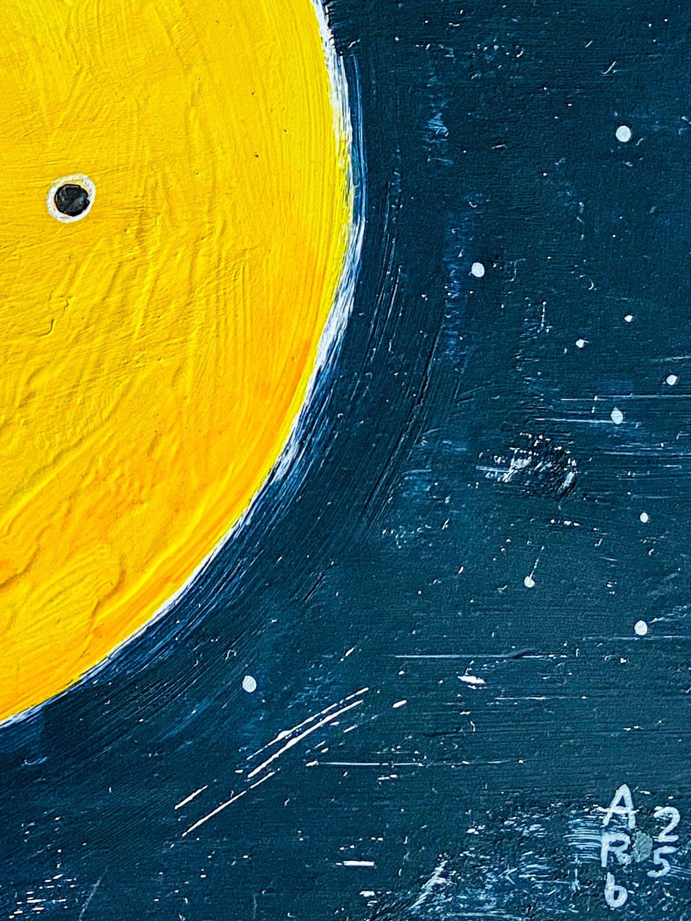 This close up image shows the details of the piece, a partial image of the moon and its small black eye.  It highlighs the various strokes and circle that create the starry details of the night sky. 