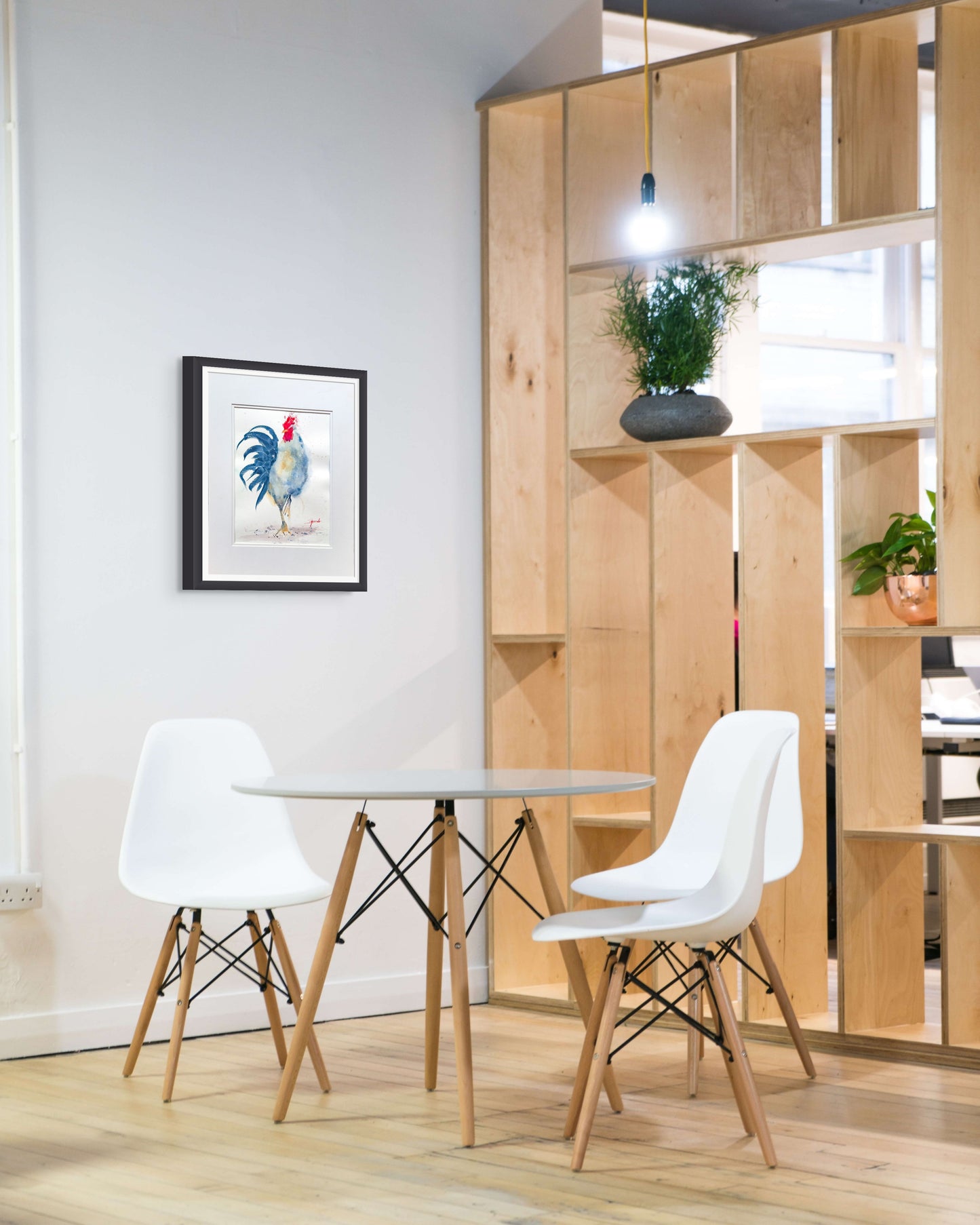 Teri's painting hangs on a wall over a small table with a wooden bookshelf on the right.