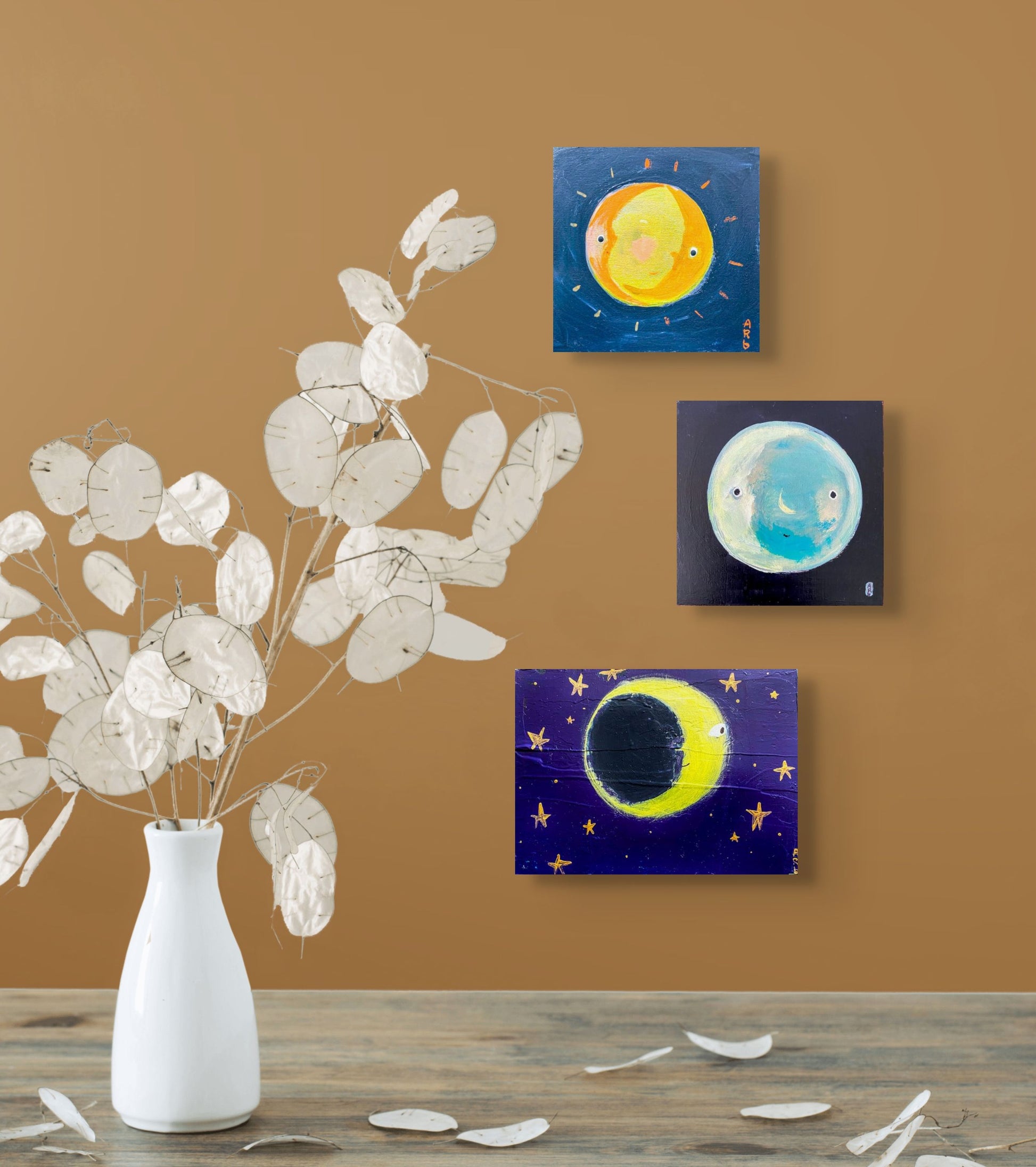 3 small moon paintings, each with dark blue background, grouped together in situ on brown wall; 