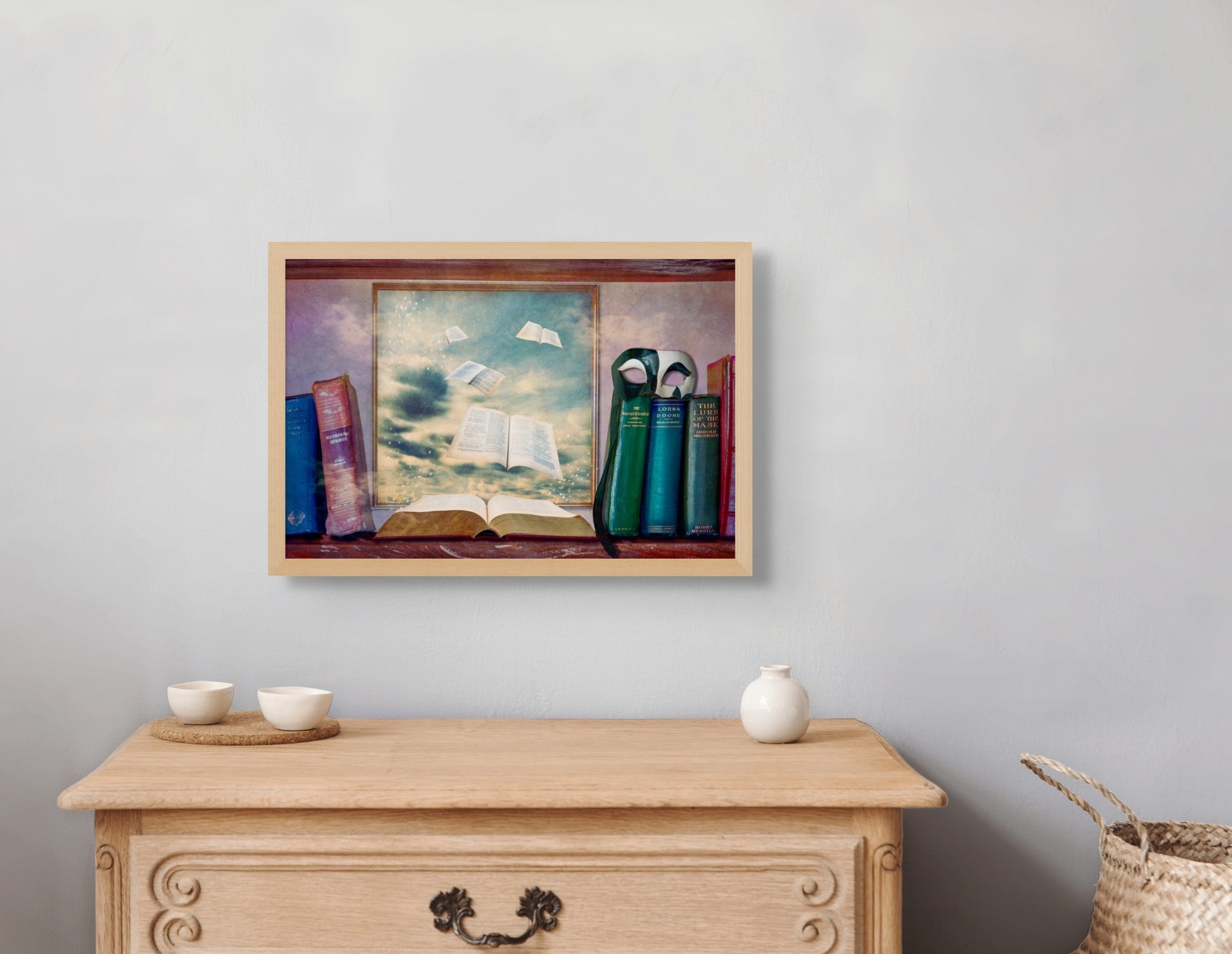 Lost Pages hangs over a small dresser, framed in a ash wooden frame which matches the dresser.  A small vase and two small bowls sit on the dresser.