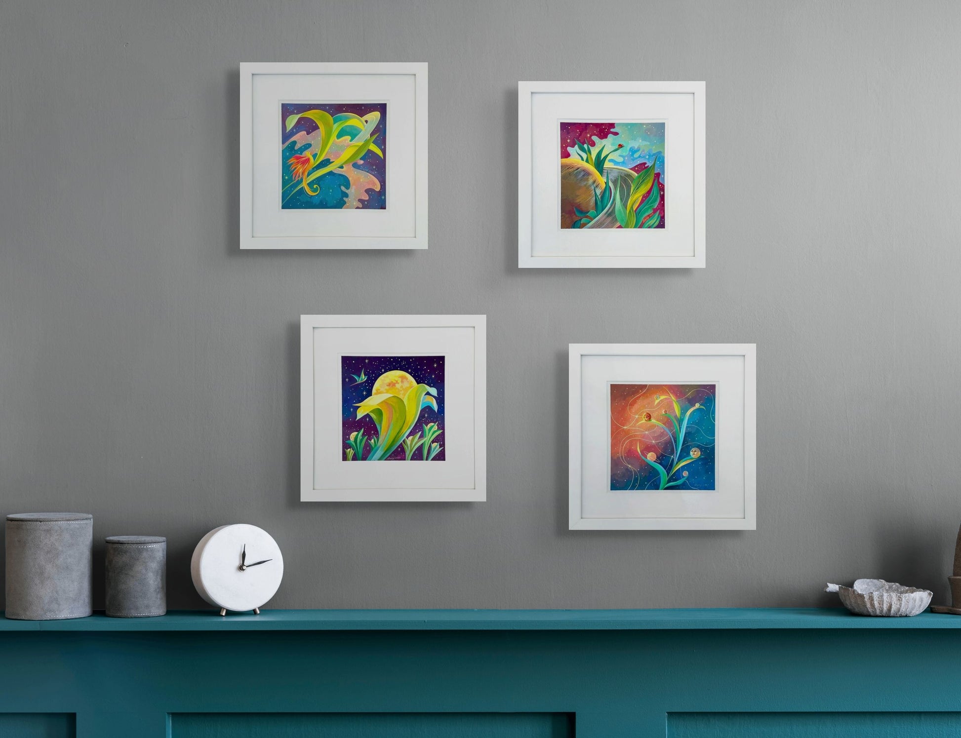 Four of Dany's Planetary Series hang above a blue wooden cabinet. The wall is light gray and the cabinet has a clock and some clay canisters sitting on top. 