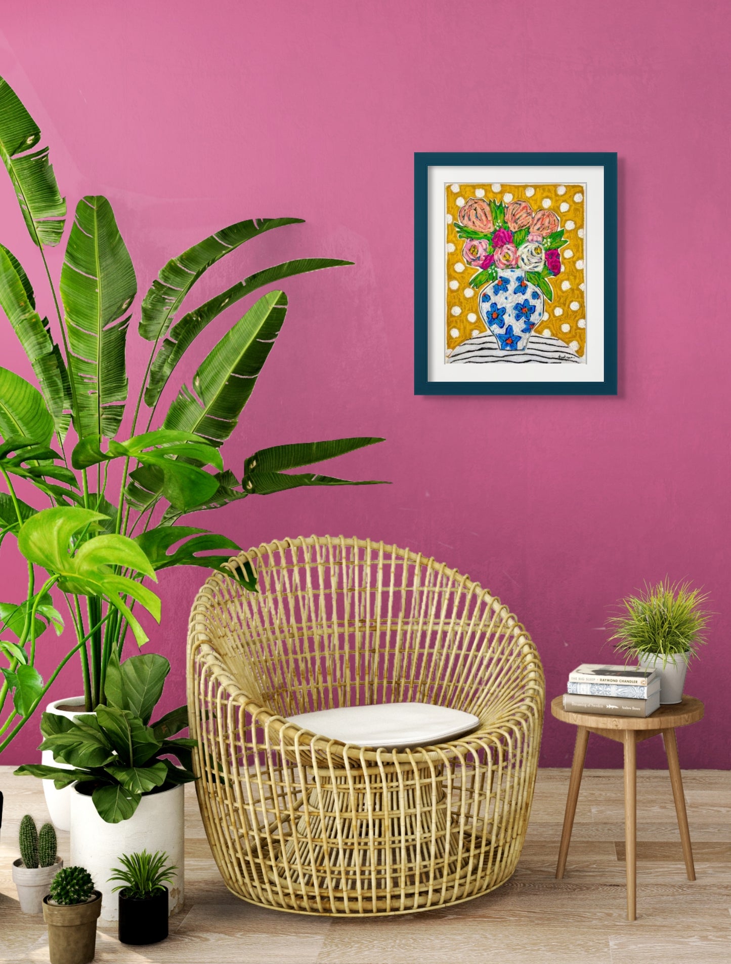 Bright and colorful acrylic and oil painting of white vase with blue flowers filled with pink, white, and peach colored flowers against a yellow background with white polka dots; artist Rachel Bunteman; shown framed in situ against pink wall