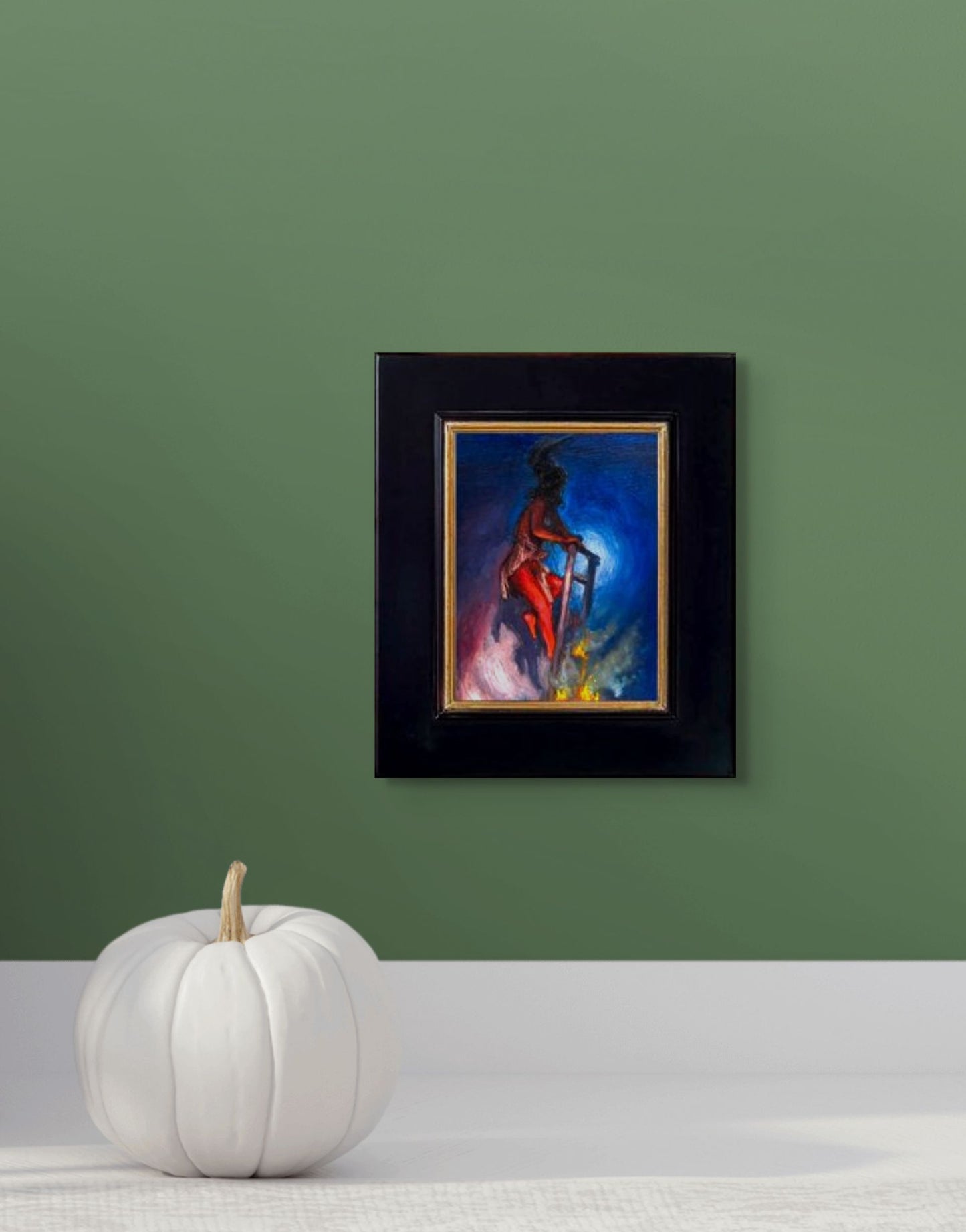 Impressionistic depiction of a person climbing a ladder appearing to go nowhere with a blue and purple background; shown with 2" black wood frame and in situ on a green wall above a white pumpkin