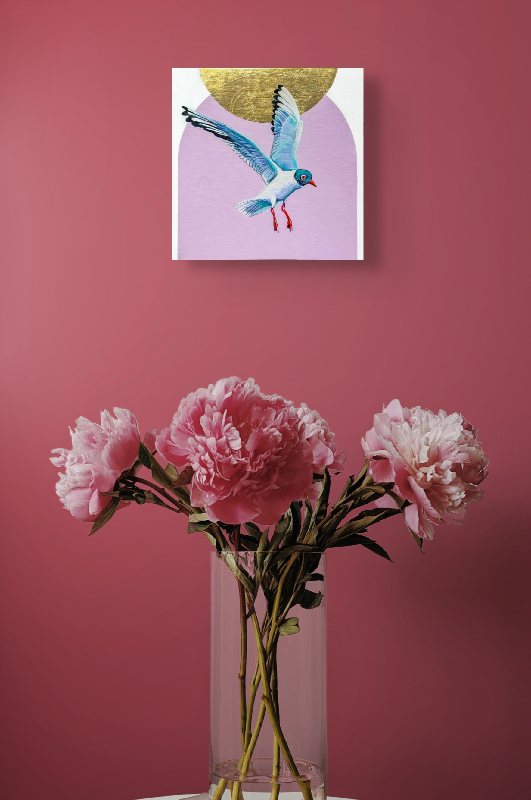 The colors in Suspended pop against this ruby red wall as it hangs above a vase of red flowers