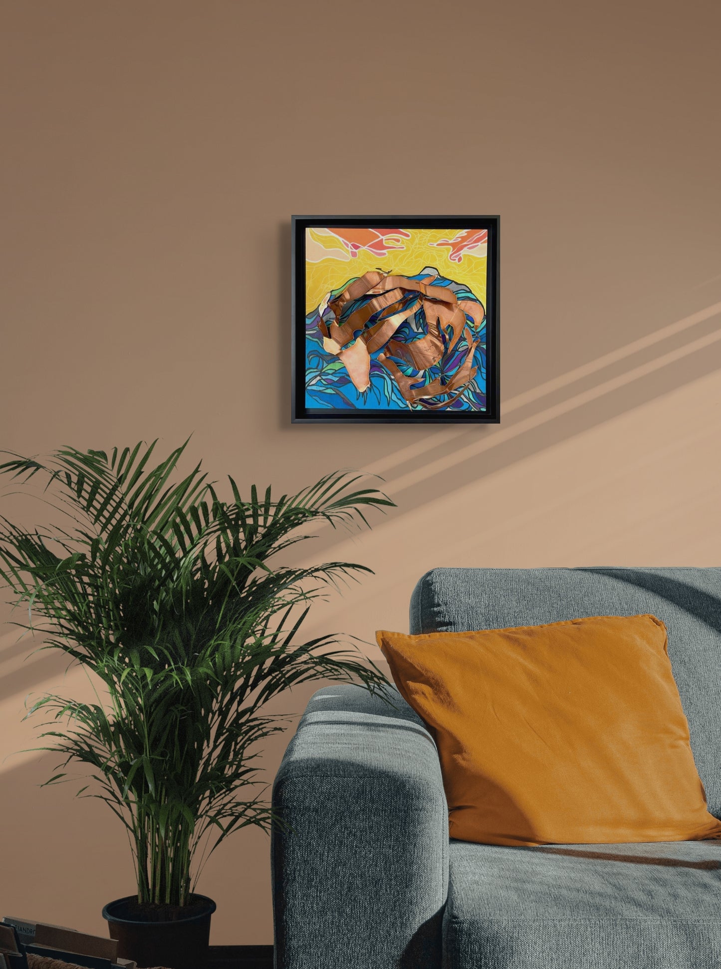 This in situ photograph shows The Ocean Within hanging on a light brown wall over a gray couch and potted plant.