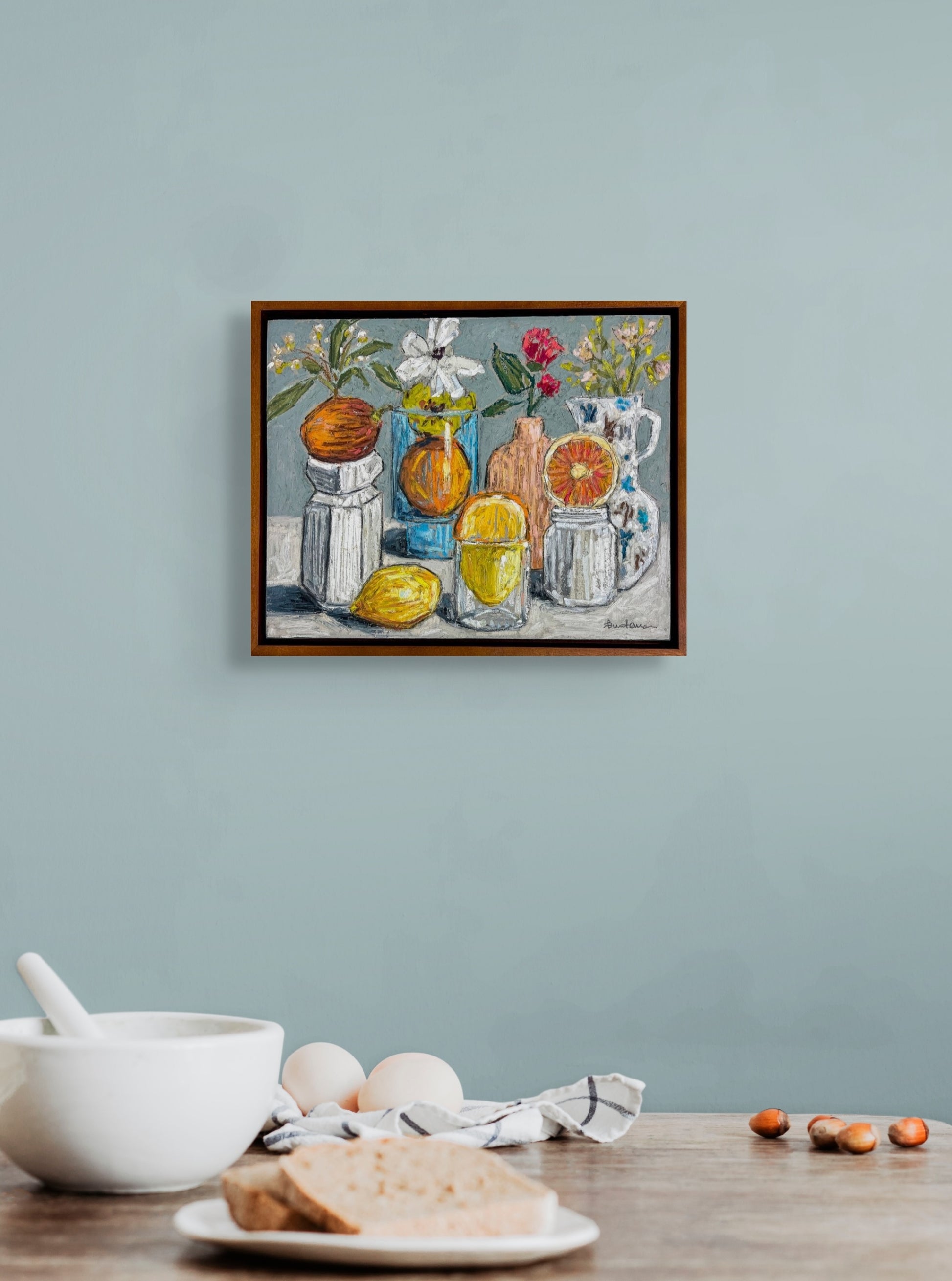 Framed still life "When the Flowers Run Out" on a light blue wall with a table in the foreground