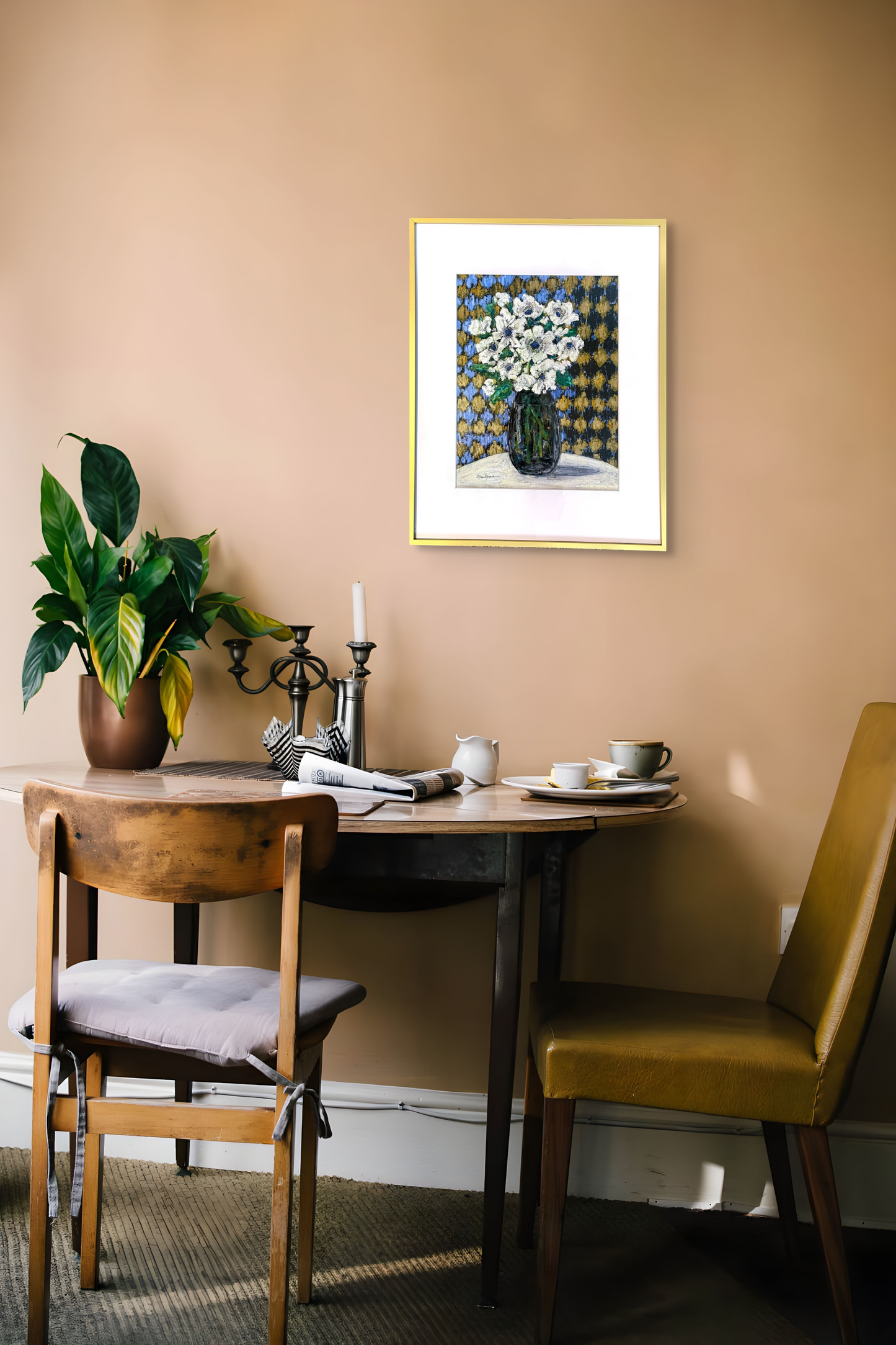 Worth the Wait looks great hanging on this light brick red wall over a small dining table adorned with a plant and mixed matched chairs.